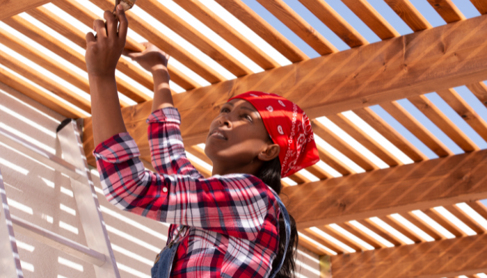 woman on ladder staining wood pergola